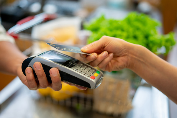 Customer pays for groceries by tapping debit card.