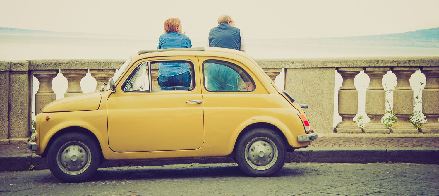 Mature couple step out of their Fiat 500 on a bridge to take in the views.