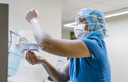 Wearing PPE, ICU nurse sanitizes her hands.